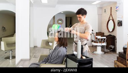 Man applying dye to womans hair in salon Stock Photo