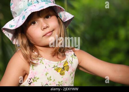 Cute European little girl in colorful Panama hat, close-up outdoor portrait Stock Photo