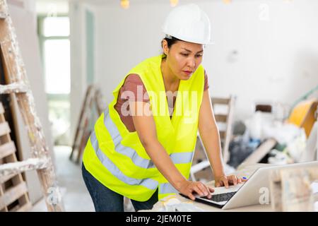 Female architect using laptop during repair works Stock Photo