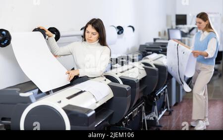 Woman working in printing office, using printer Stock Photo