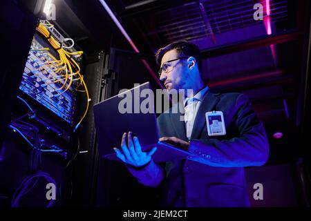 Low angle portrait of professional network engineer setting up servers in data center Stock Photo