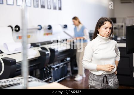 Technician operator calibrating plotter machine, typing on computer keyboard Stock Photo