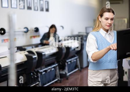 Technician operator calibrating plotter machine, typing on computer keyboard Stock Photo