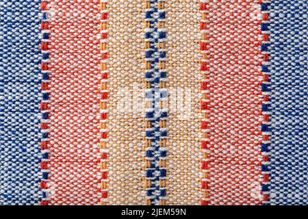 Plain weave fabric background macro. Cloth with vertical stripes of yellow, red and blue colors. Textile texture surface detail. Design element. Stock Photo