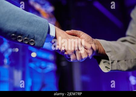 Close up of two business people shaking hands with data center interior in background Stock Photo