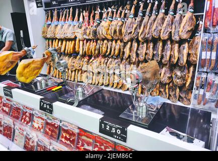 Hanging cured hams on the wall in a Spanish supermarket Stock Photo