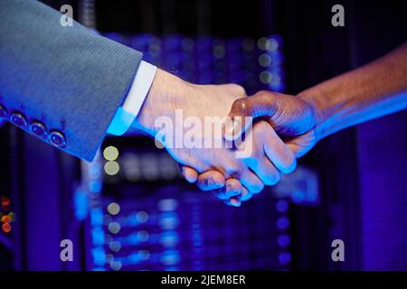 Close up of employer shaking hands with employee in server room interior Stock Photo