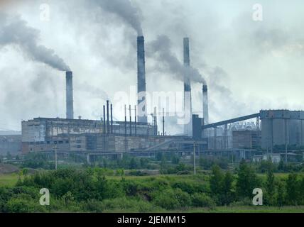 The old plant for the production of mineral fertilizers. Smoking and spewing steam pipes Stock Photo