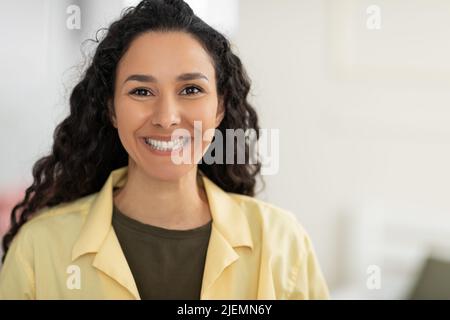 Potrait of happy millennial long-haired woman in casual outfit looking at camera and smiling indoors, copy space Stock Photo