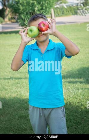 Funny boy covered his eyes with apples. Vertical shot. Stock Photo