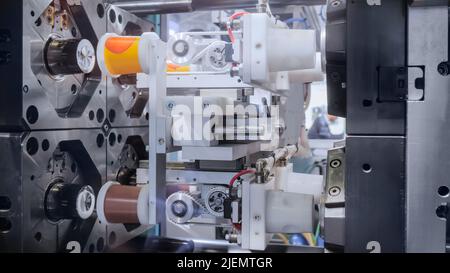 Injection molding machine during work: production of empty plastic pots ...