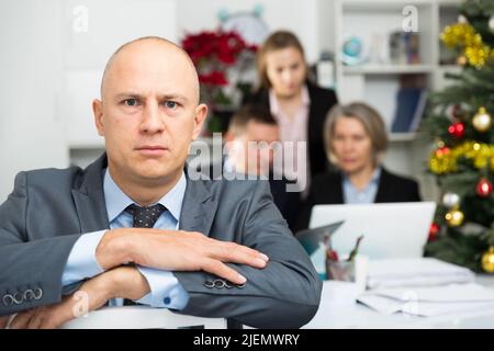 Business team tensely solving problems in office with offended man foreground Stock Photo