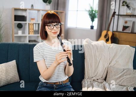 A music teacher conducts a lesson on playing a musical instrument over the Internet. Flute lessons online and online music training during quarantine for the coronavirus pandemic. Stock Photo