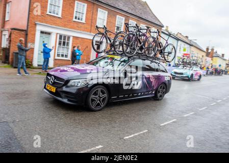 Team service cars, vehicles supporting the UCI Women’s Tour cycle race Stage 1 as it passes through High Street, Hadleigh, Suffolk. Wet road from rain Stock Photo
