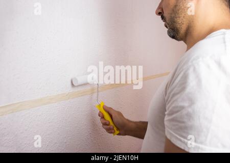 Hispanic man painting the wall with paint roller Stock Photo