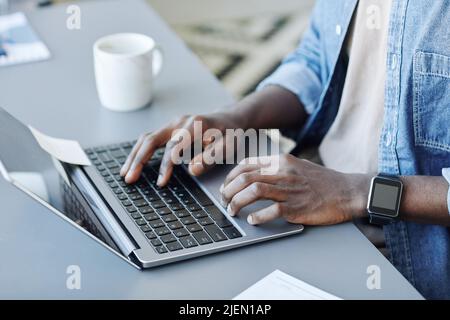 Close up of young black man typing at laptop keyboard while working remotely from home, copy space Stock Photo