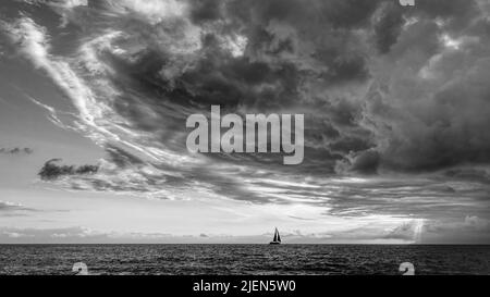 A Storm Is Looming Overhead As A Small Boat Moves Toward The Shining Light Black And White Stock Photo