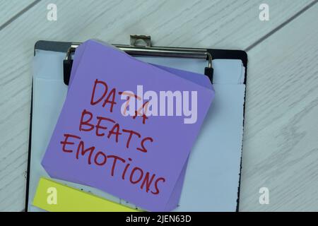 Concept of Data Beats Emotions write on sticky notes isolated on Wooden Table. Stock Photo