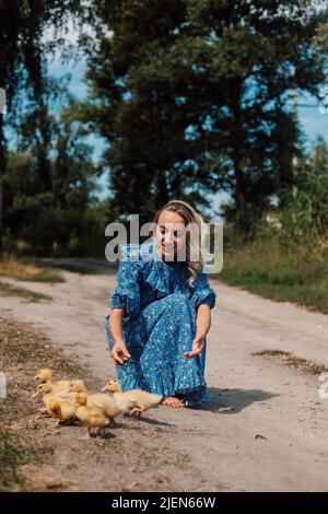 Beautiful farmer woman caring for little ducklings in the woods Stock Photo