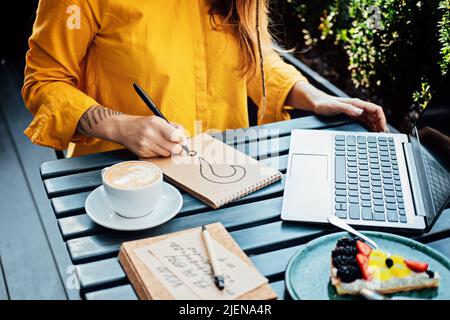 Freelancer problem challenges, Finding work, Finding clients. Freelancer woman working with laptop and writing question mark in notepad while sitting Stock Photo