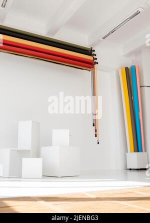 Sunny daylight photo studio interior with set rolls of color background and white cubes as a photo requisite. Stock Photo