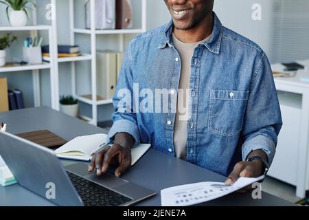 Cropped portrait of young data scientist using laptop computer in office and smiling Stock Photo
