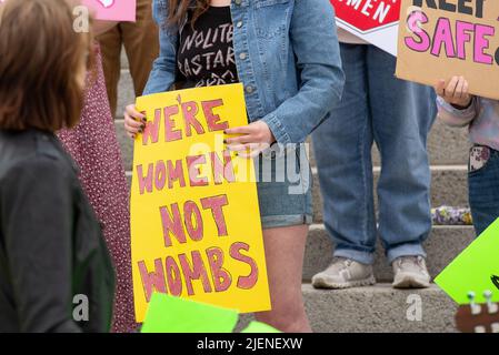 Helena, Montana - June 24, 2022: woman holds we're women not wombs sign protesting abortion ban, pro choice protest at Montana state capitol, demonstr