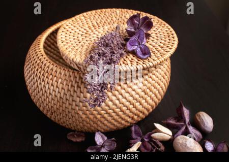 wicker rattan box craft round on top with dried flowers and lavender on a black background Stock Photo