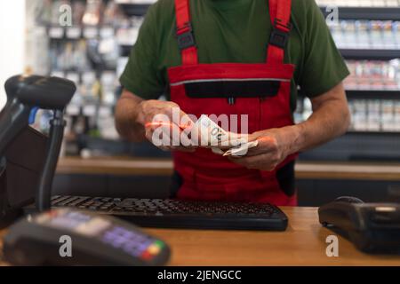 Employee taking cash payment from costumer in gas station, close-up Stock Photo
