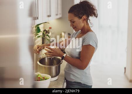 A woman prepares dough in the kitchen with a dough mixer Stock Photo