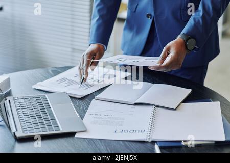 Closeup of unrecognizable African American businessman analyzing financial report with budget documents in foreground, copy space Stock Photo