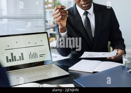 Cropped shot of successful black businessman analyzing financial report at workplace in office, copy space Stock Photo