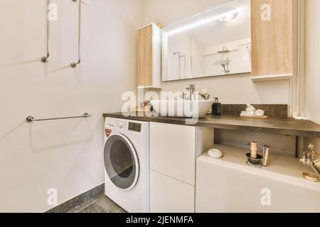 Shower in a bright bathroom with a washing machine and a sink with a mirror with wooden cabinets Stock Photo