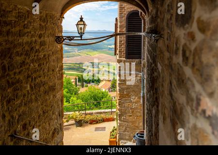 View through an arched tunneled passageway of the hills of Tuscany from a staircase in the historic medieval hill town of Volterra, Italy. Stock Photo