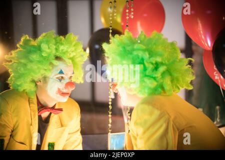 Man with crazy green face paint, big red lips & a green wig at The