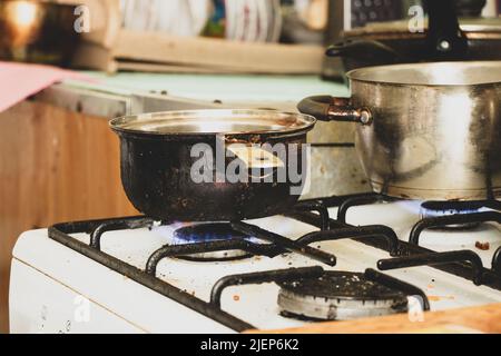 a dirty saucepan stands on a dirty gas stove in the kitchen at home, cooking soup on the stove, gas stove, kitchen Stock Photo