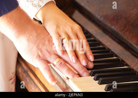 hands of newlyweds with wedding gold rings on the piano close-up, wedding photo, wedding rings on fingers Stock Photo