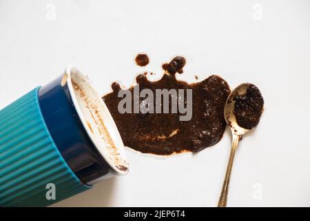 a cup with overturned coffee on a white background and a teaspoon lies next to it, spilled coffee on a white background Stock Photo