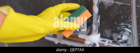 A hand with a yellow wash sponge washes the very dirty greasy surface ...
