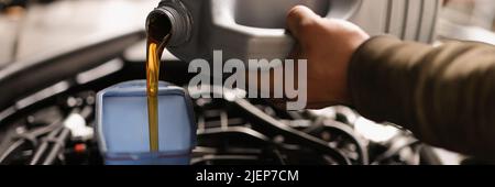 A man pours engine oil from a canister into a car Stock Photo