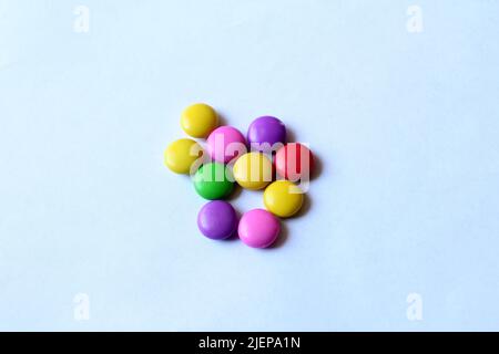 Selective focus of a pile of colorful chocolate buttons on a white paper background. Stock Photo