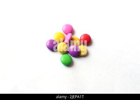 Selective focus of a pile of colorful chocolate buttons on a white paper background. Stock Photo