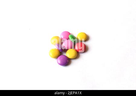 Selective focus of a pile of colorful chocolate buttons on a white paper background. Stock Photo