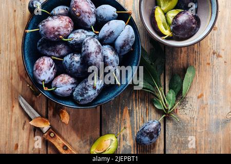 A bowl of fresh blue plums on a wooden background. Stock Photo