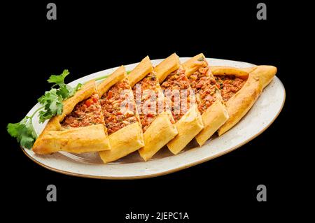 turkish pizza pide with minced meat lies on a plate on a black isolated background Stock Photo