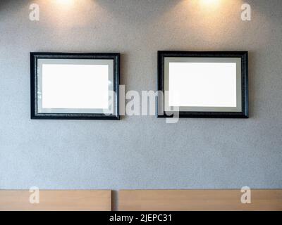 Two empty white blank pictures of luxury wood photo frames set hanging on grey stone wall background. Mockup vintage frames on grey background. Stock Photo