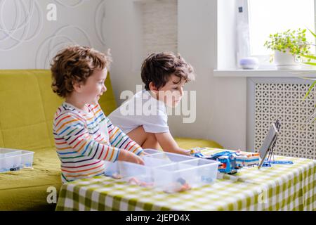 Kid collects robot from plastics details and programmed on tablet, robotics. Stock Photo