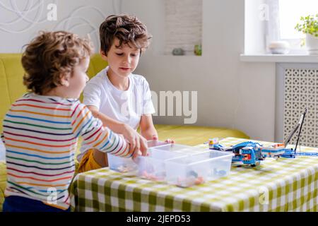 Kid collects robot from plastics details and programmed on tablet, robotics. Stock Photo