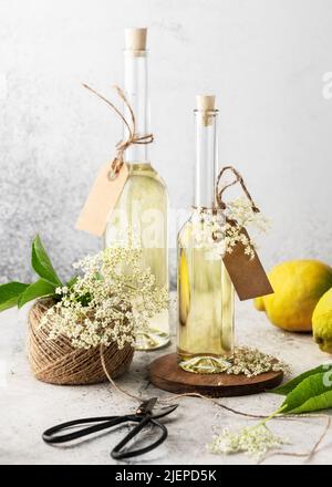 Homemade elderflower syrup in glass bottles for summer drink with elder flower buds and lemon. Organic drinks concept. Selective focus. Stock Photo