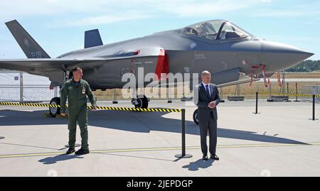 22 June 2022, Brandenburg, Schönefeld: German Chancellor Olaf Scholz (SPD) stands in front of an Italian Armed Forces F-35 fighter aircraft during the opening tour of the ILA International Aerospace Exhibition. The Lockheed Martin F-35 Lightning II is a fifth-generation stealth multirole fighter that emerged from the U.S. Department of Defense's Joint Strike Fighter program. The federal government has purchased 35 jets of the U.S. aircraft, which will replace the Tornado. The air show at Schönefeld Airport will be open from June 22-26, 2022. On the left, the pilot of the aircraft. Photo: Wolfg Stock Photo